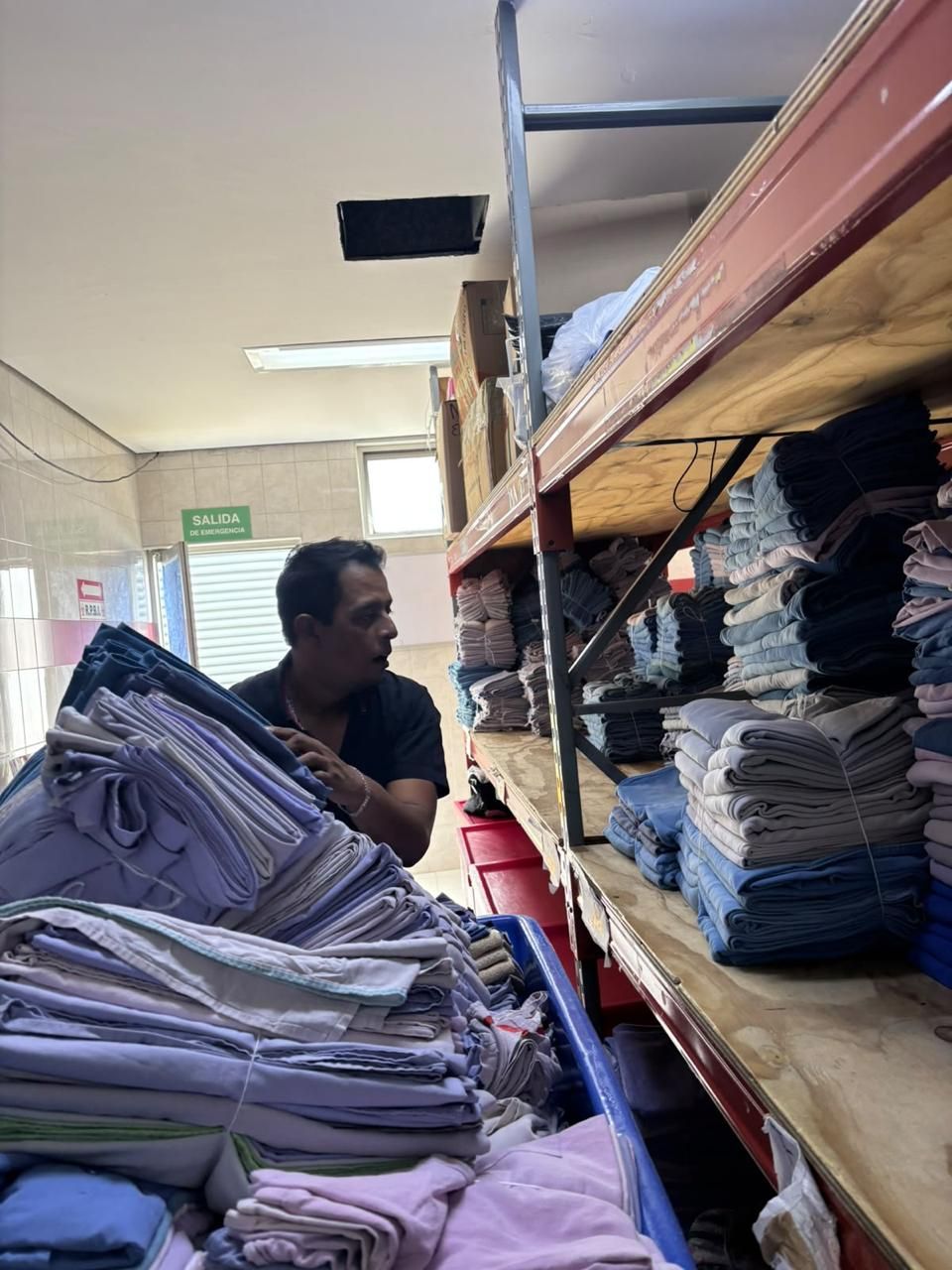 Personal de Tomaquet acomodando ropa hospitalaria doblada